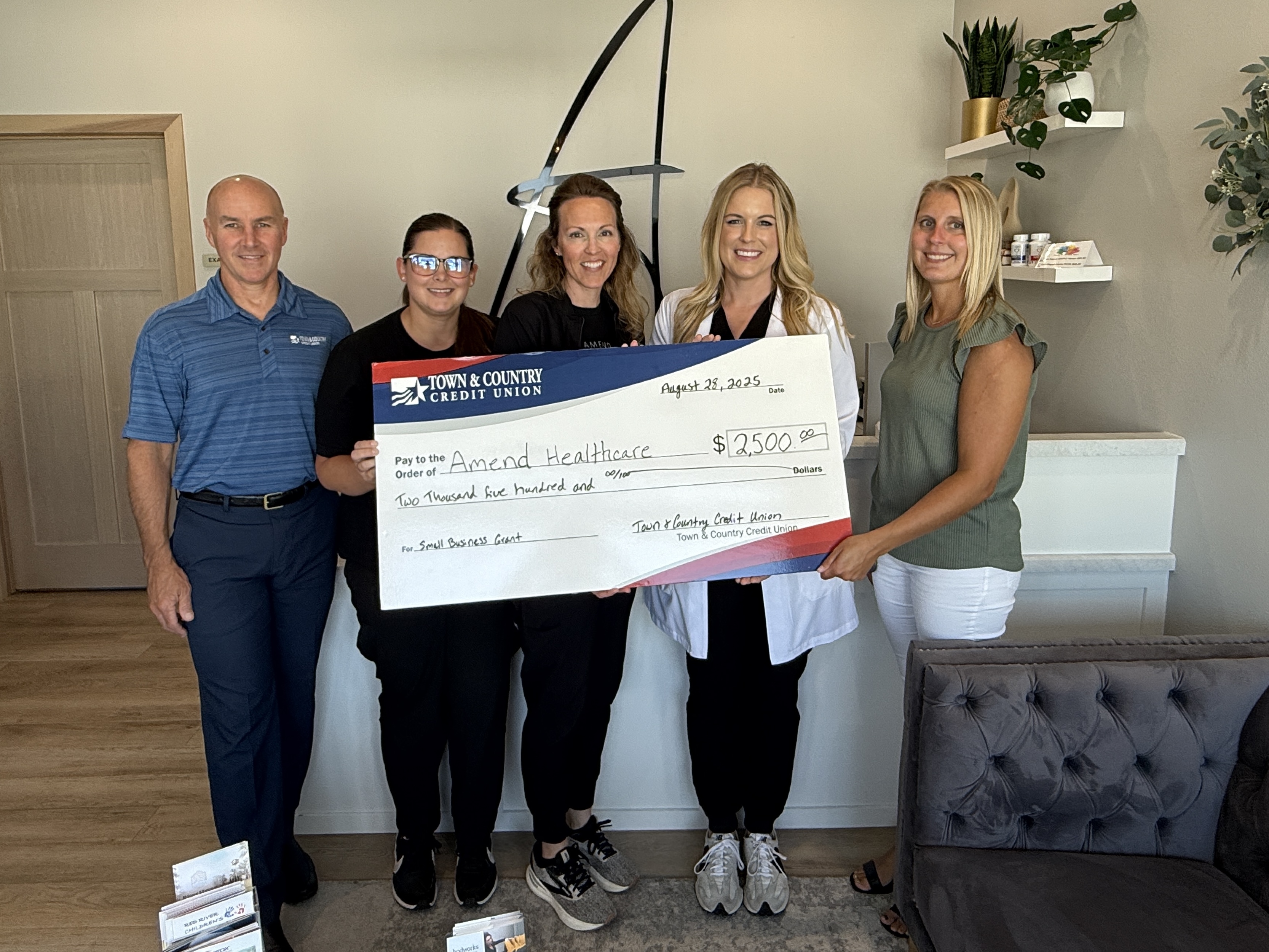 Group of people holding a large check in a healthcare office.