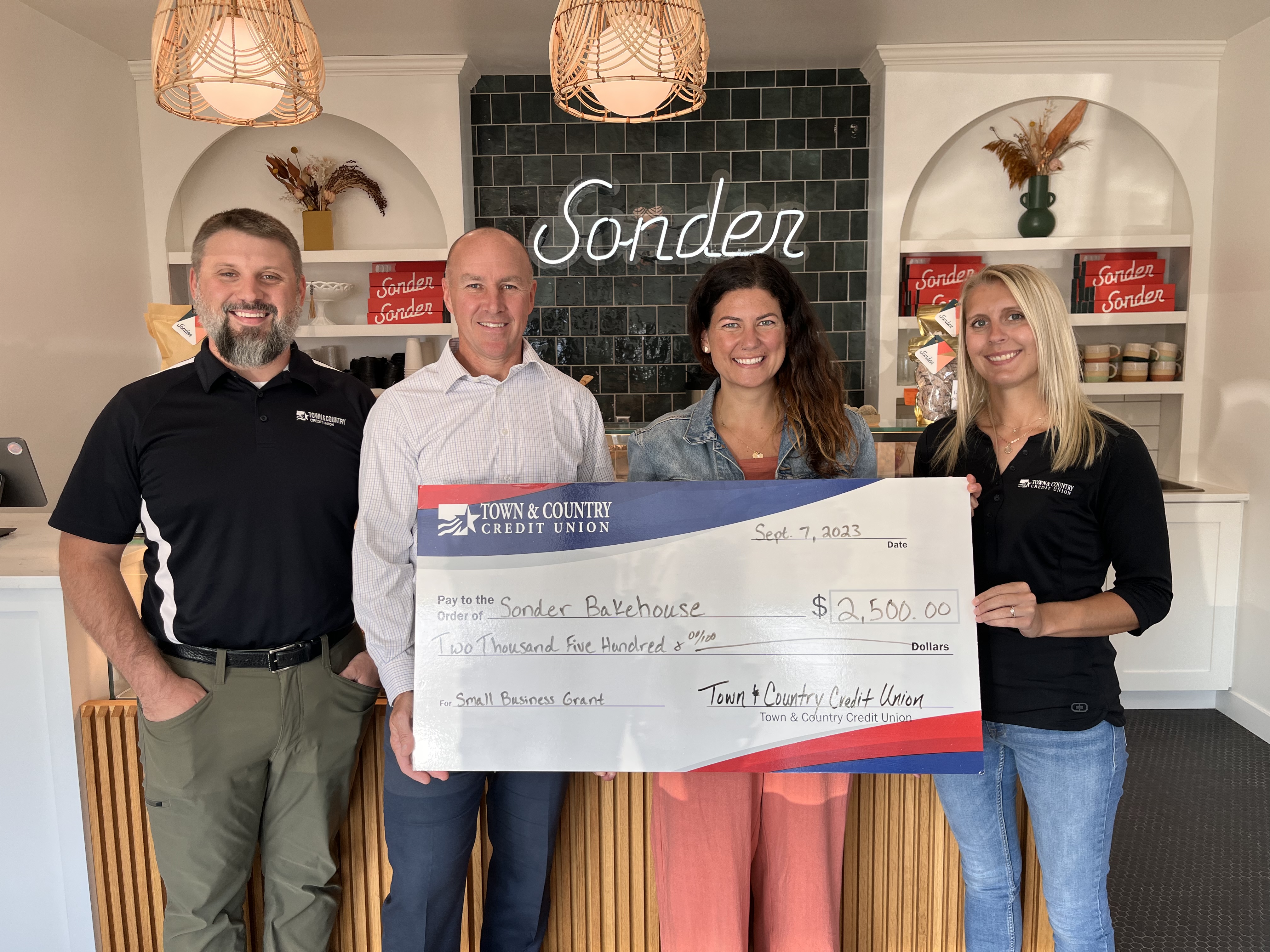 Town & Country staff presenting a large ceremonial check to Sonder Bakehouse